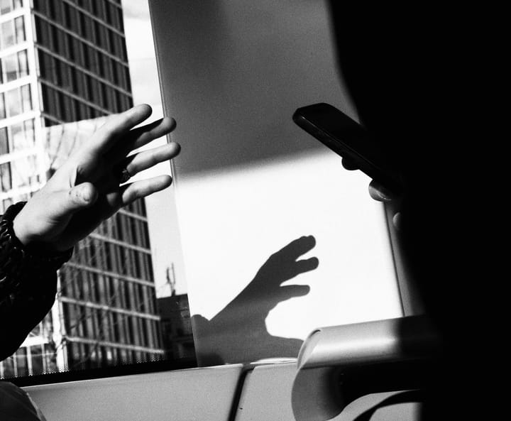 Hands reaching out in the dark one holding a smartphone